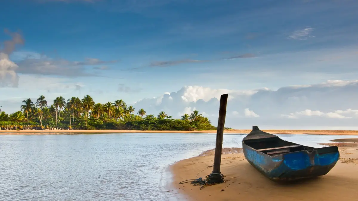 Canoa na margem do rio cercada pela natureza de Caraíva